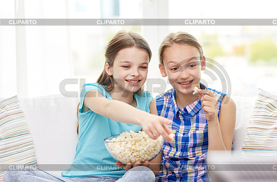 Happy girls with popcorn watching tv at home | High resolution stock photo |ID 5224256